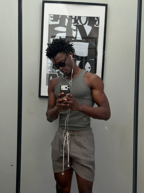 Man with smartphone and earbuds captured in London mirror reflection