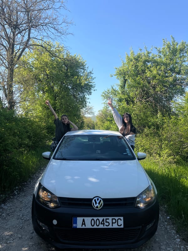 Two people pose with white Volkswagen in rural Bulgaria