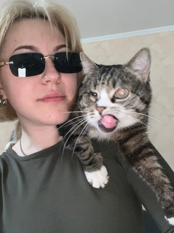 Person poses for selfie with tabby cat on shoulder