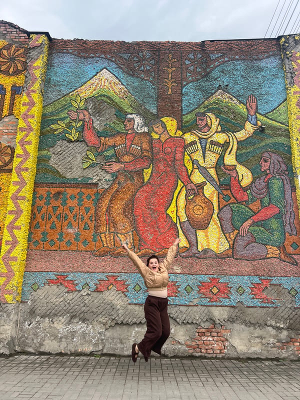 Woman poses, dances at outdoor mosaic mural, picks leaves