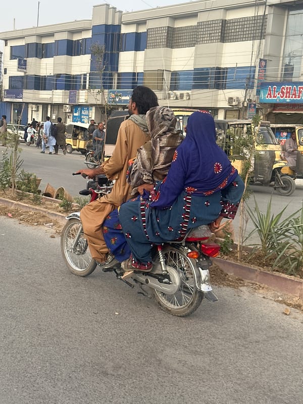 Busy street life in Quetta: motorcycles, pedestrians, and decorated rickshaws