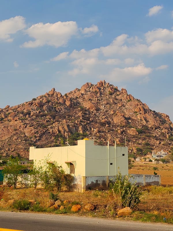 Daytime view captures beige building against rocky hills in Sanjivapuram