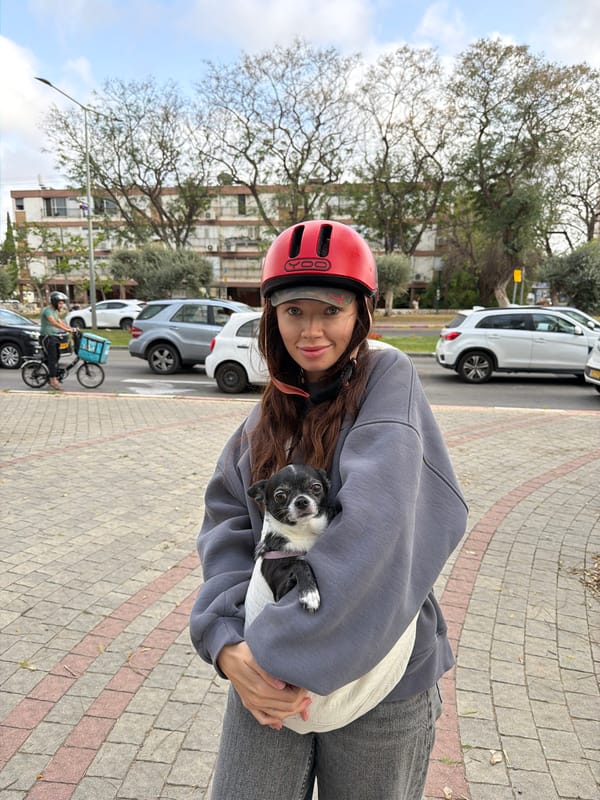 Couple cycles with small dog through Ramat Gan area