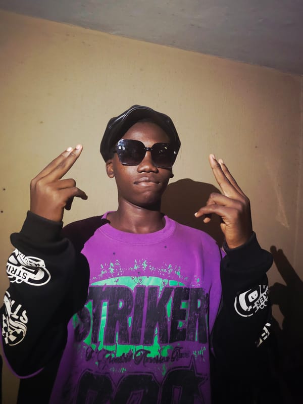 Young man in graphic shirt photographed indoors in Nkwelle