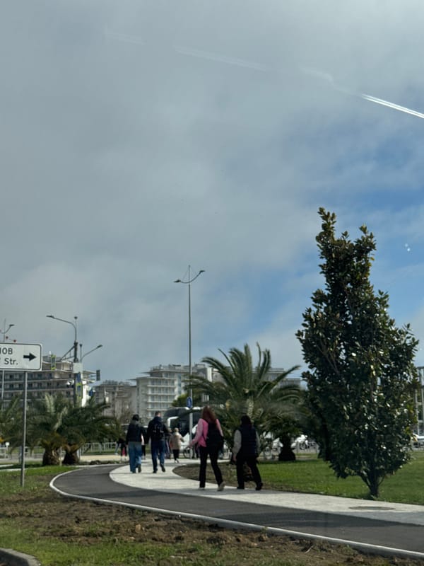 Pedestrians walk sidewalk in Sirius, Russia under cloudy skies