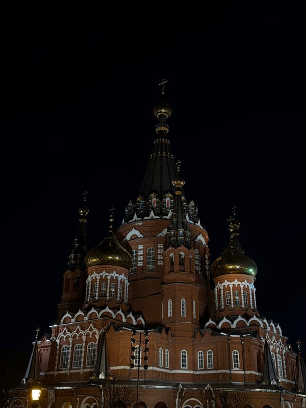 Evening pedestrian spotted near illuminated cathedral in Izhevsk