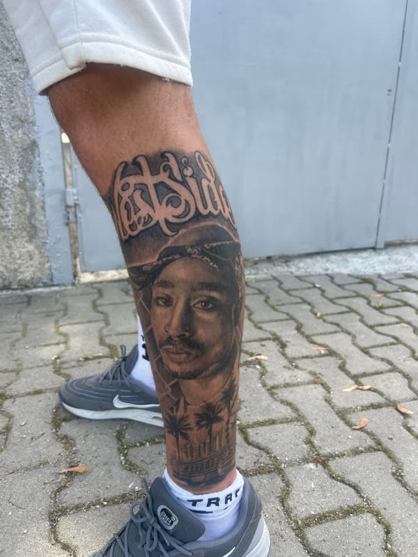 Person shows off Tupac and wolf tattoos on arm