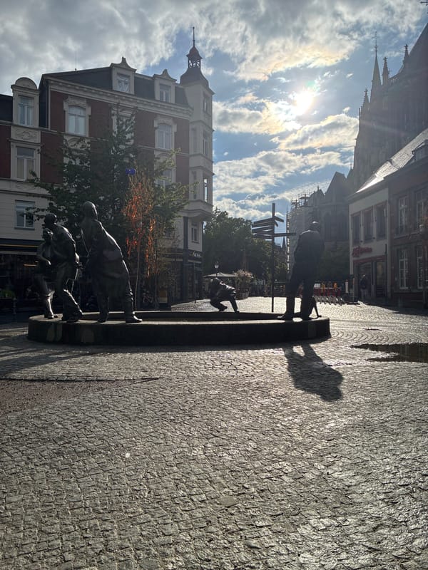 Visitors document sunny afternoon at Aachen's historic Bahkauv fountain