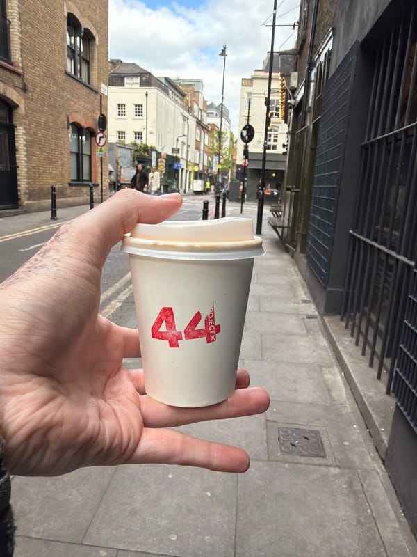 Coffee cup held on London street amid mixed architecture