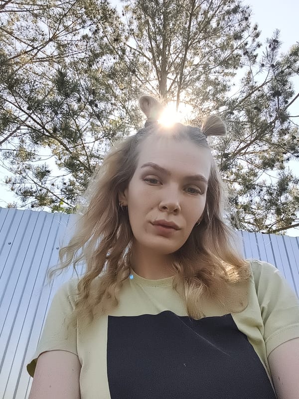 Blonde-haired person photographed in two-toned shirt in Russian village