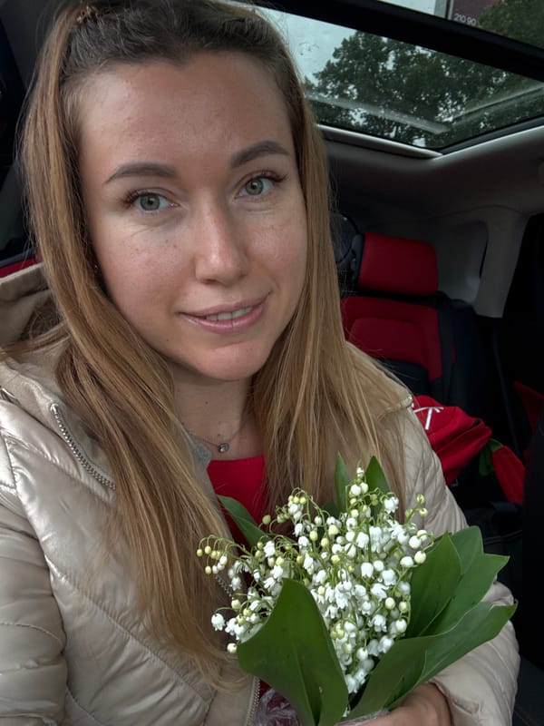 Woman with lily bouquet photographed smiling in red-seated car