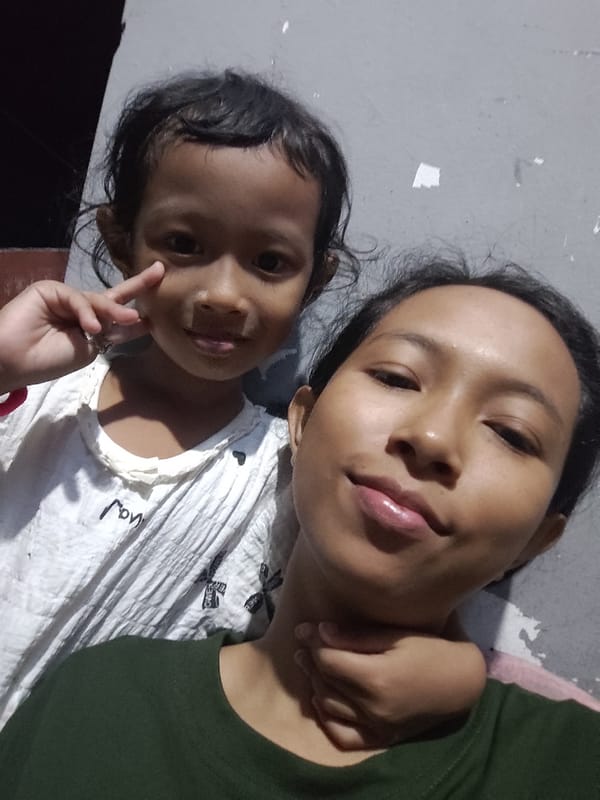 Close selfie against a gray wall, two people together