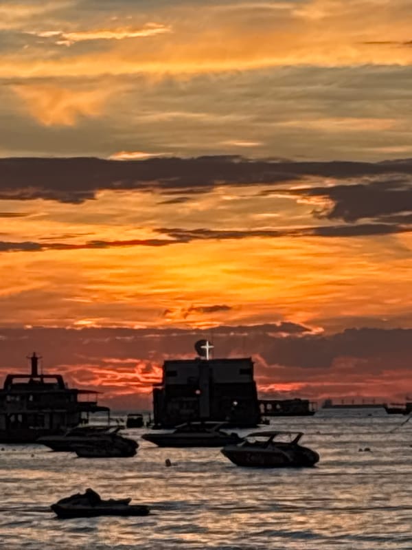 Sunset over Pattaya Bay with boats on calm water