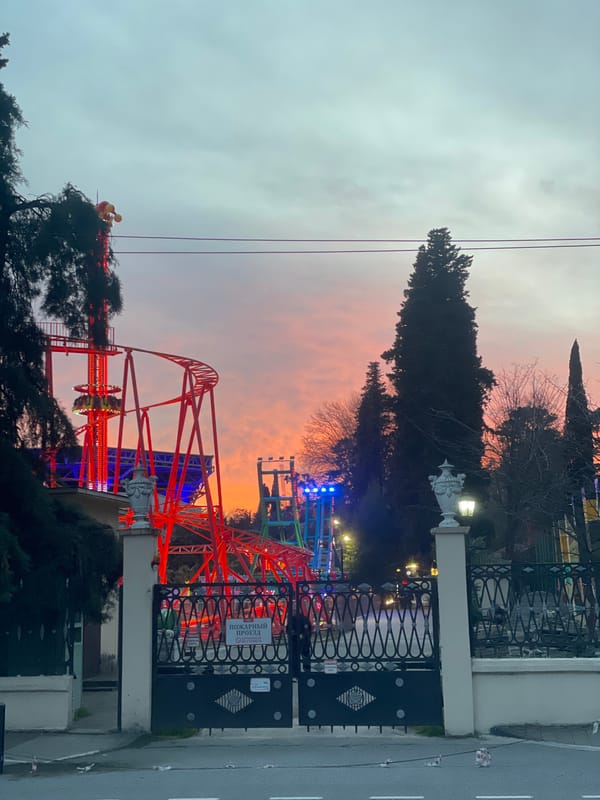 Amusement park roller coaster viewed through gate in Sochi