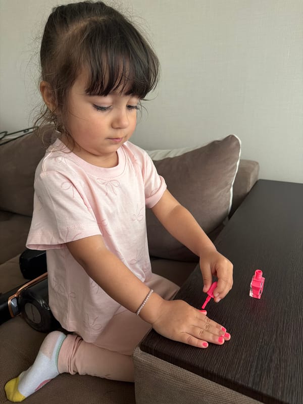 Young girl paints fingernails pink in Burgas home