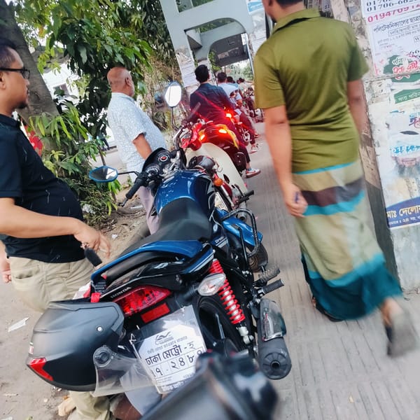 Motorcycles parked on Dhaka street with people gathering nearby