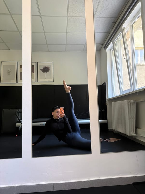Woman performs yoga pose in fitness studio mirror selfie