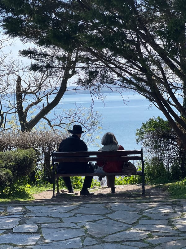 Two people sit on bench overlooking water in Burgas