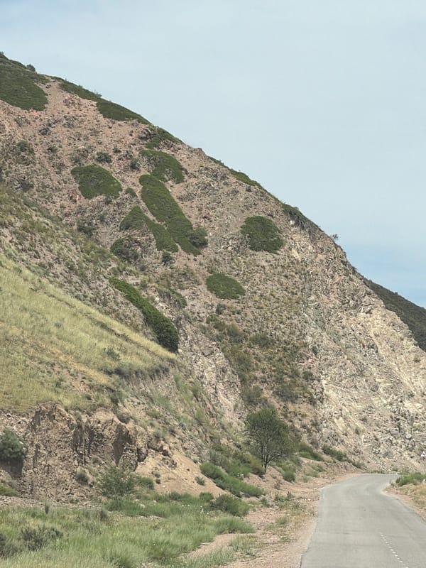 Mountain road journey past dry hills, villages, and a river valley