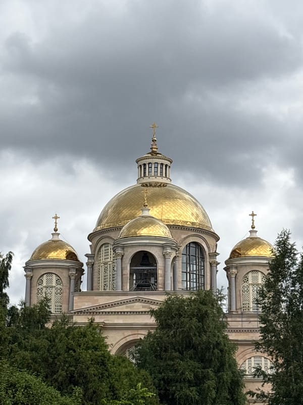 Golden domes of a Saint Petersburg Orthodox cathedral under grey skies