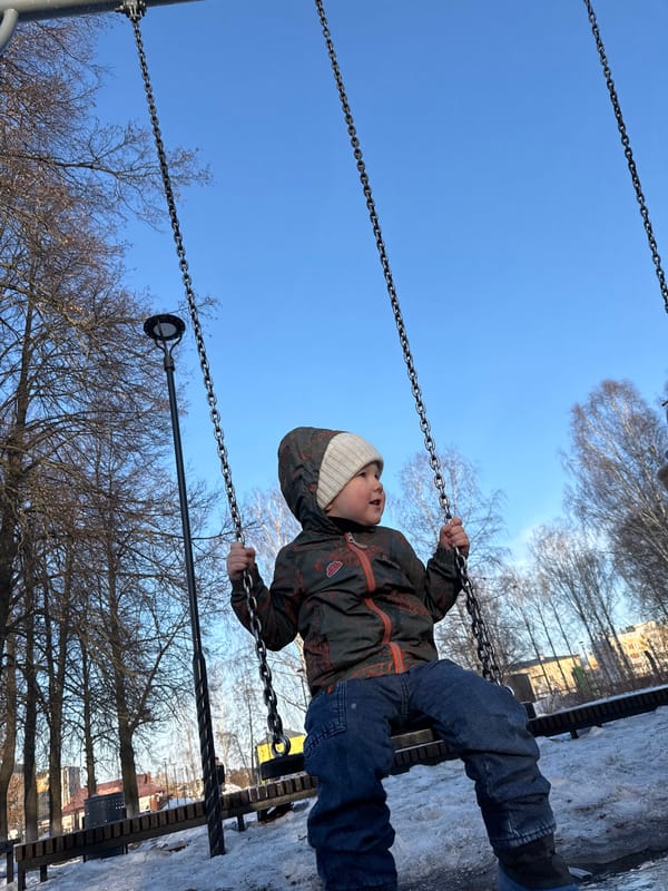 Child plays on swing in snowy playground in Russia