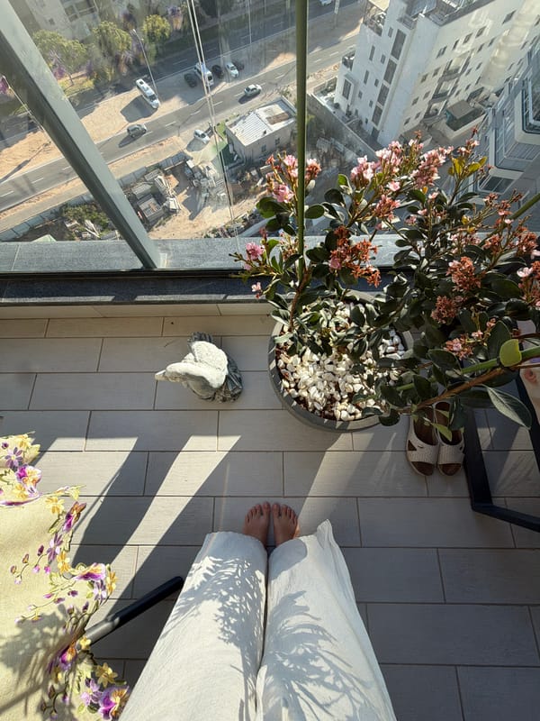 Person relaxes on balcony overlooking Ashdod on sunny afternoon