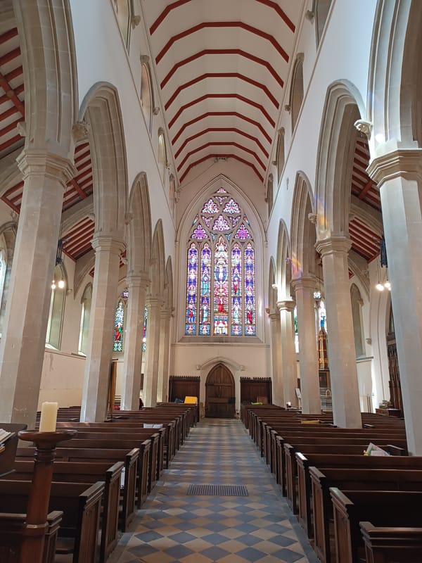 Church interior with vaulted ceilings, carved pews, and checkered floors