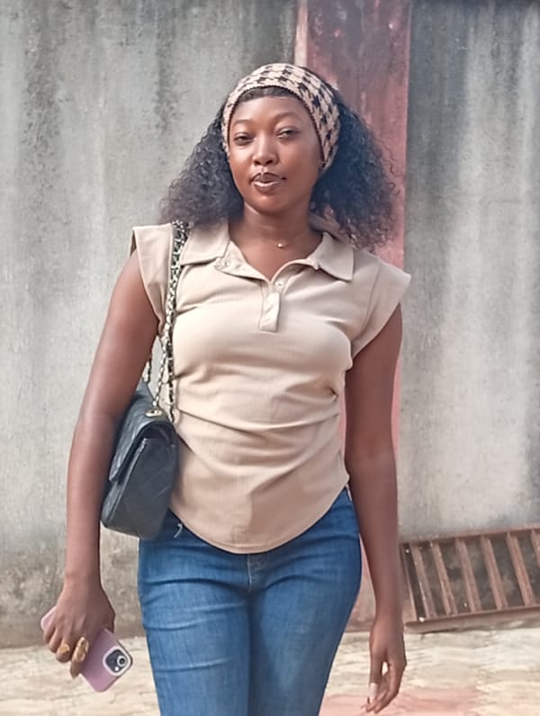 Woman photographed standing by concrete wall with smartphone