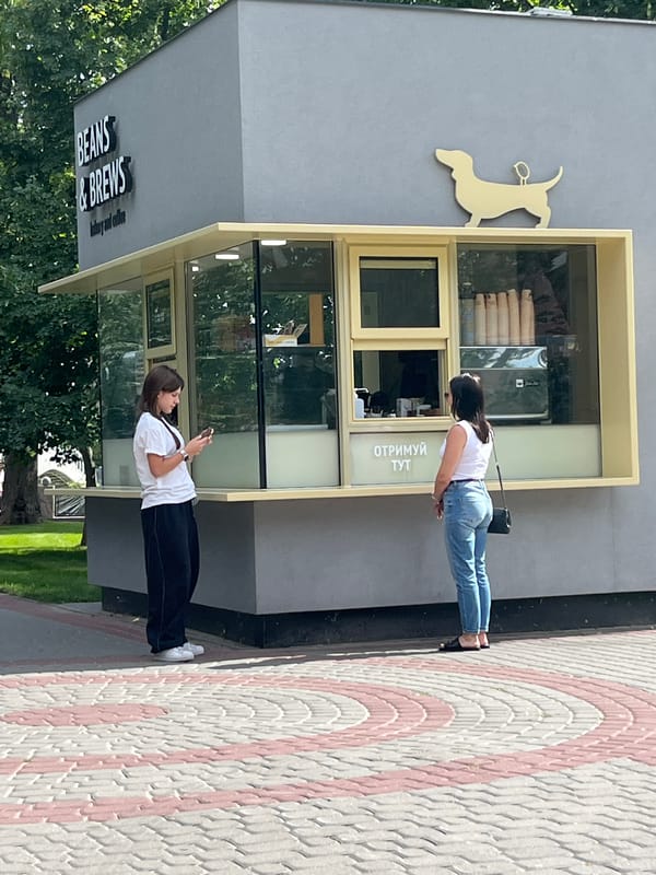 Coffee kiosk, open lawns, and a flower-ringed statue in a public park