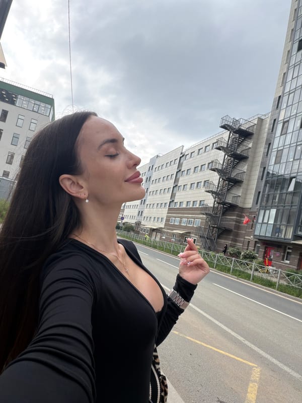 Woman stands with eyes closed on Saint Petersburg sidewalk