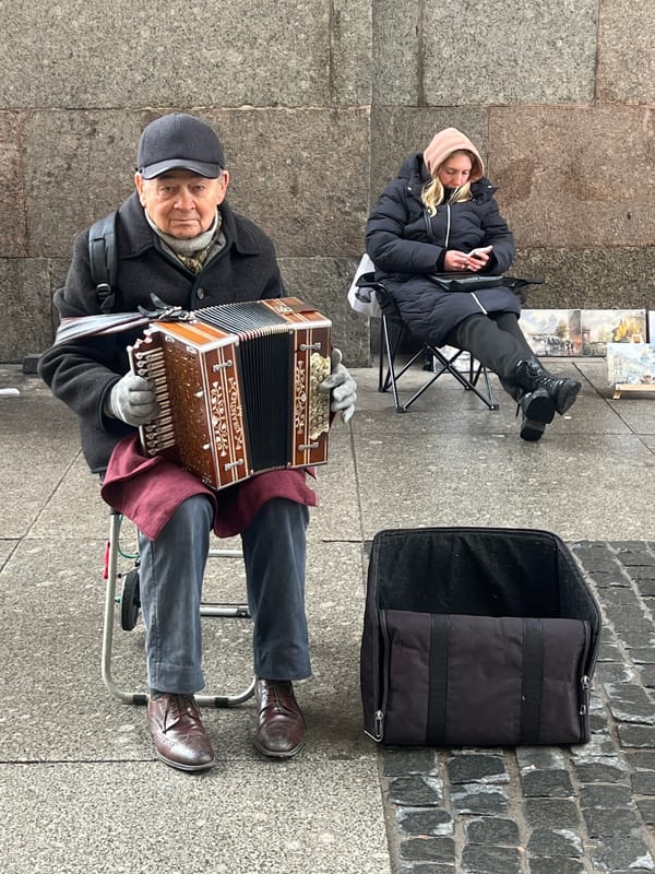 Street musician performs accordion amid paintings in Saint Petersburg