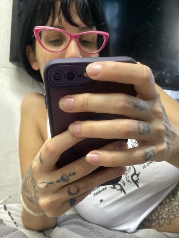Person with pink glasses uses purple-cased phone in Buenos Aires
