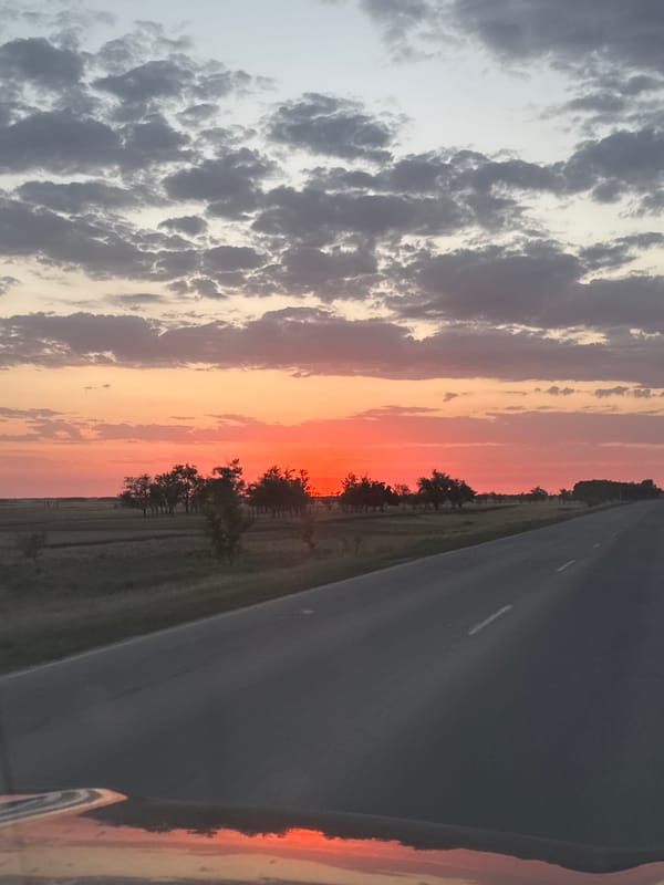 Sunset over a Kazakh highway, sky ablaze with orange and pink