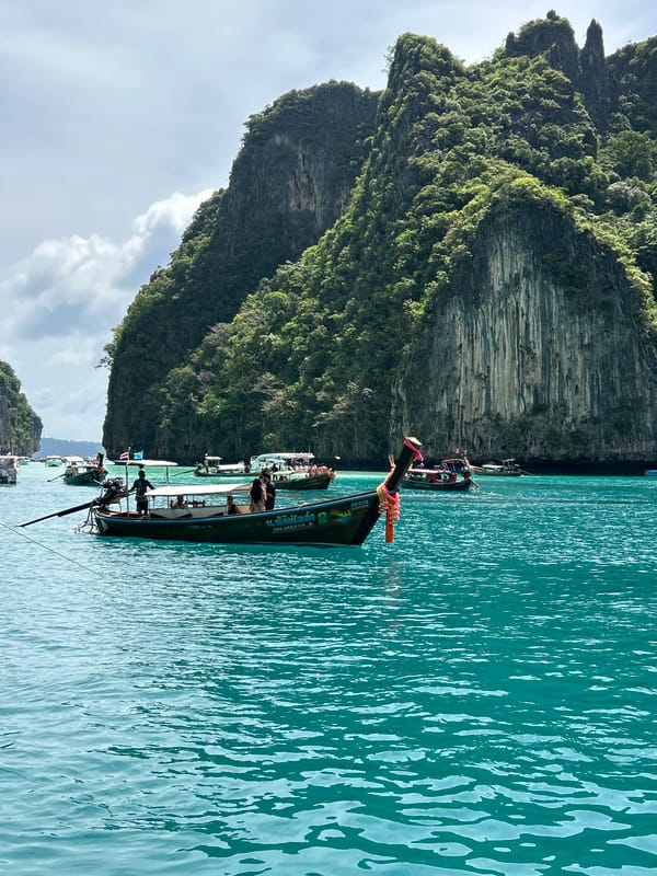Boats and swimmers in Ao Nang's limestone-framed bay