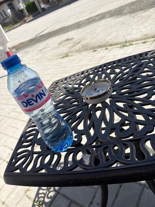 Outdoor table setup: water, cigarettes, and a lighter near a Bike Center