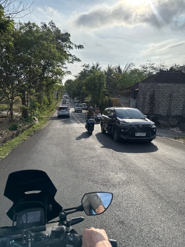 Motorcycle rider observes parked SUV on Kuta Selatan street