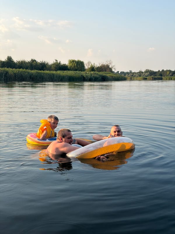 Lake day in Ukraine: swimmers, a pier, and a dog in a shark vest