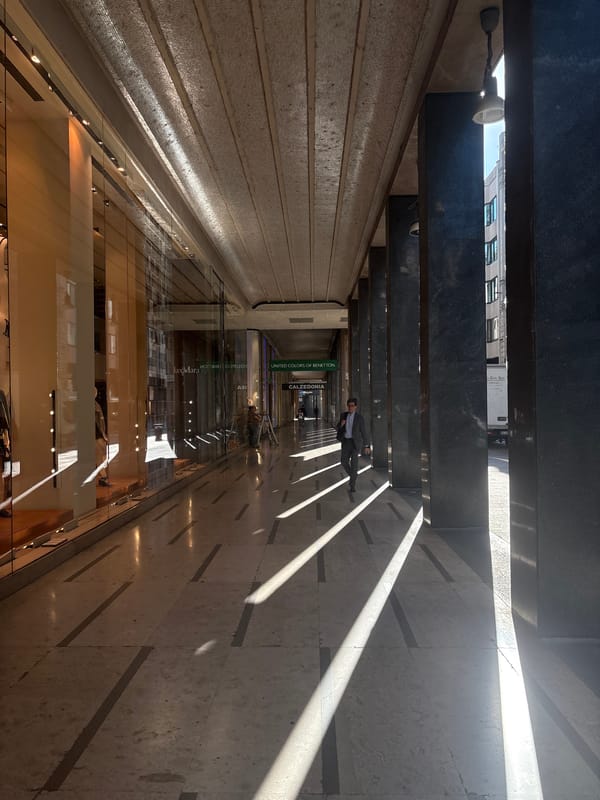 Milan morning: arcade shadows and an Apple Store plaza
