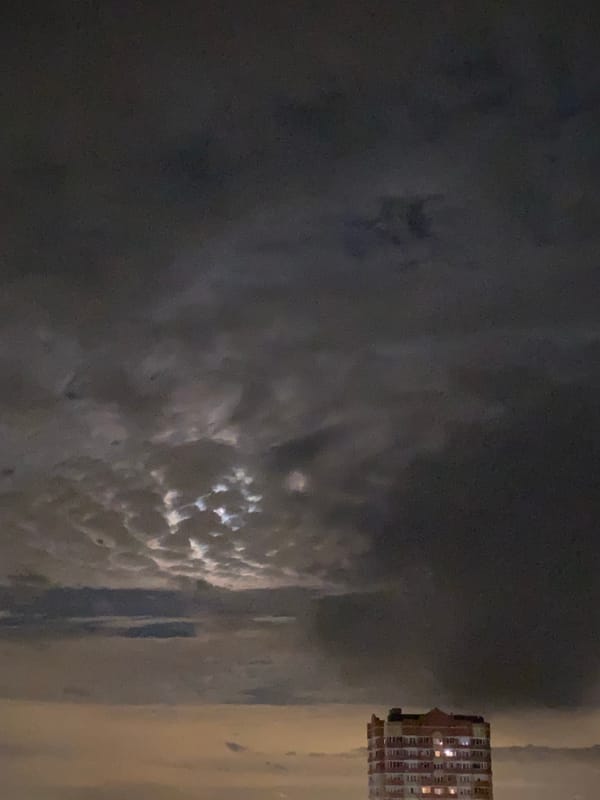 Light breaks through dark clouds in nighttime sky