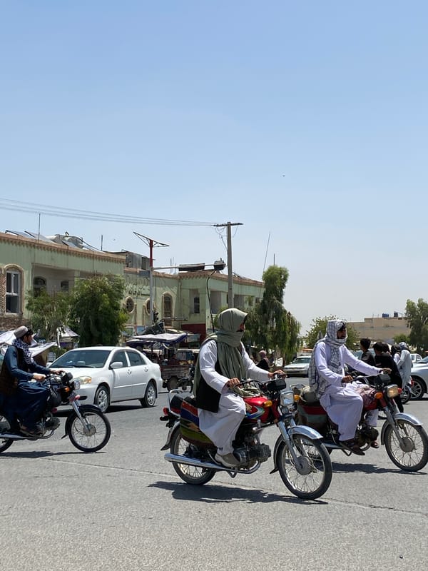 Motorcycles moving through a sunny Kandahar street