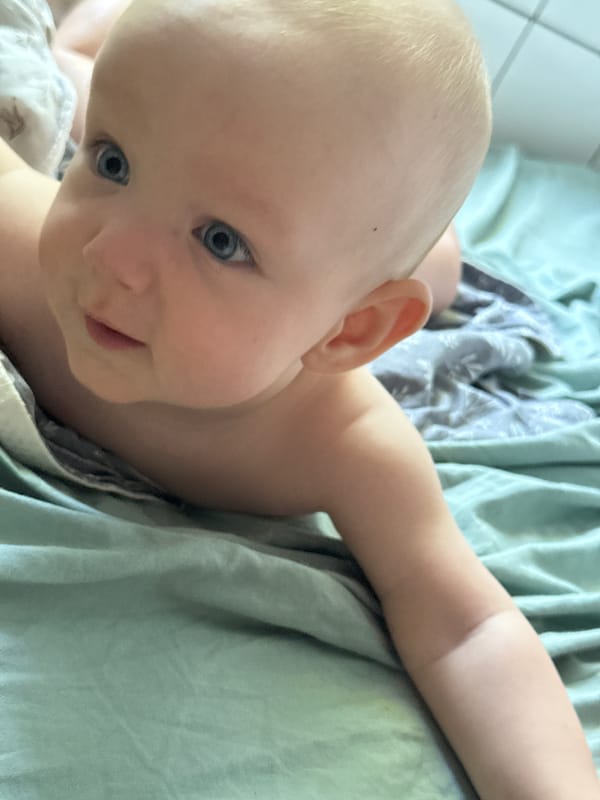 Baby on green-sheeted bed in Sochi, moving around