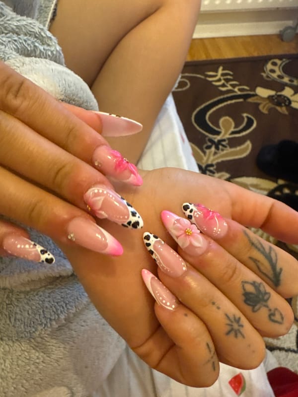 Detailed acrylic nail art with pink French tips and 3D accents