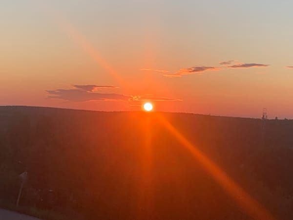Sunset fades over a forested horizon at dusk