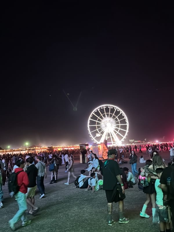 Nighttime crowds gather at Coachella festival with illuminated Ferris wheel