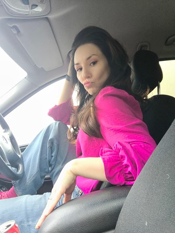 Woman sits in car during early morning rain in Riga