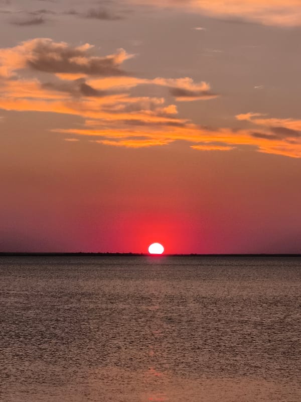 Sunset over urban waterfront, captured from a promenade