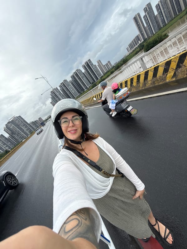 Scooter stop on a rainy Huizhou bridge, city skyline behind