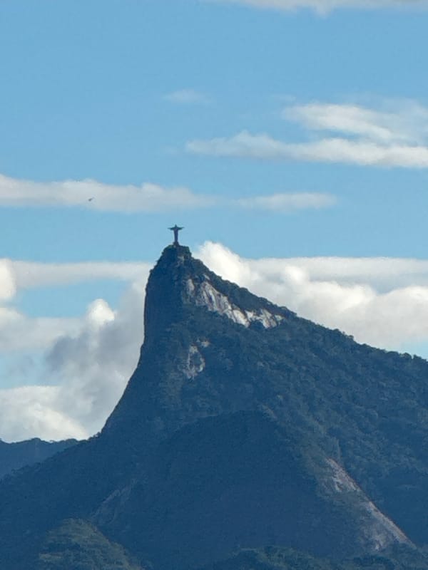 Christ the Redeemer silhouetted against blue sky from Niterói