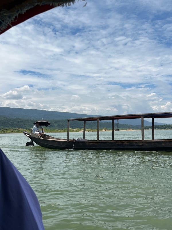 Boat ride along a green river through hilly northeast India