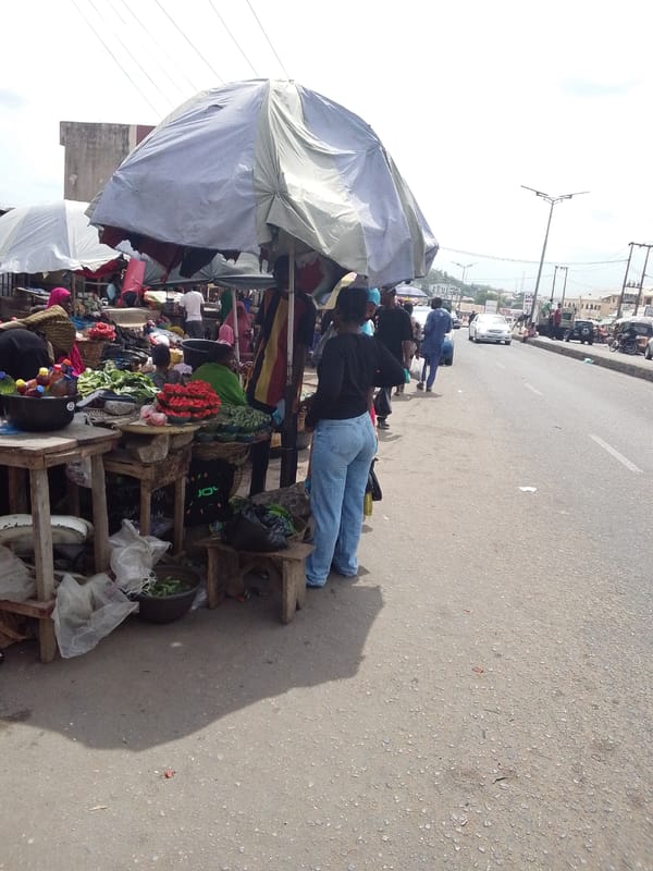 Daily street commerce and community gathering documented in Adankolo